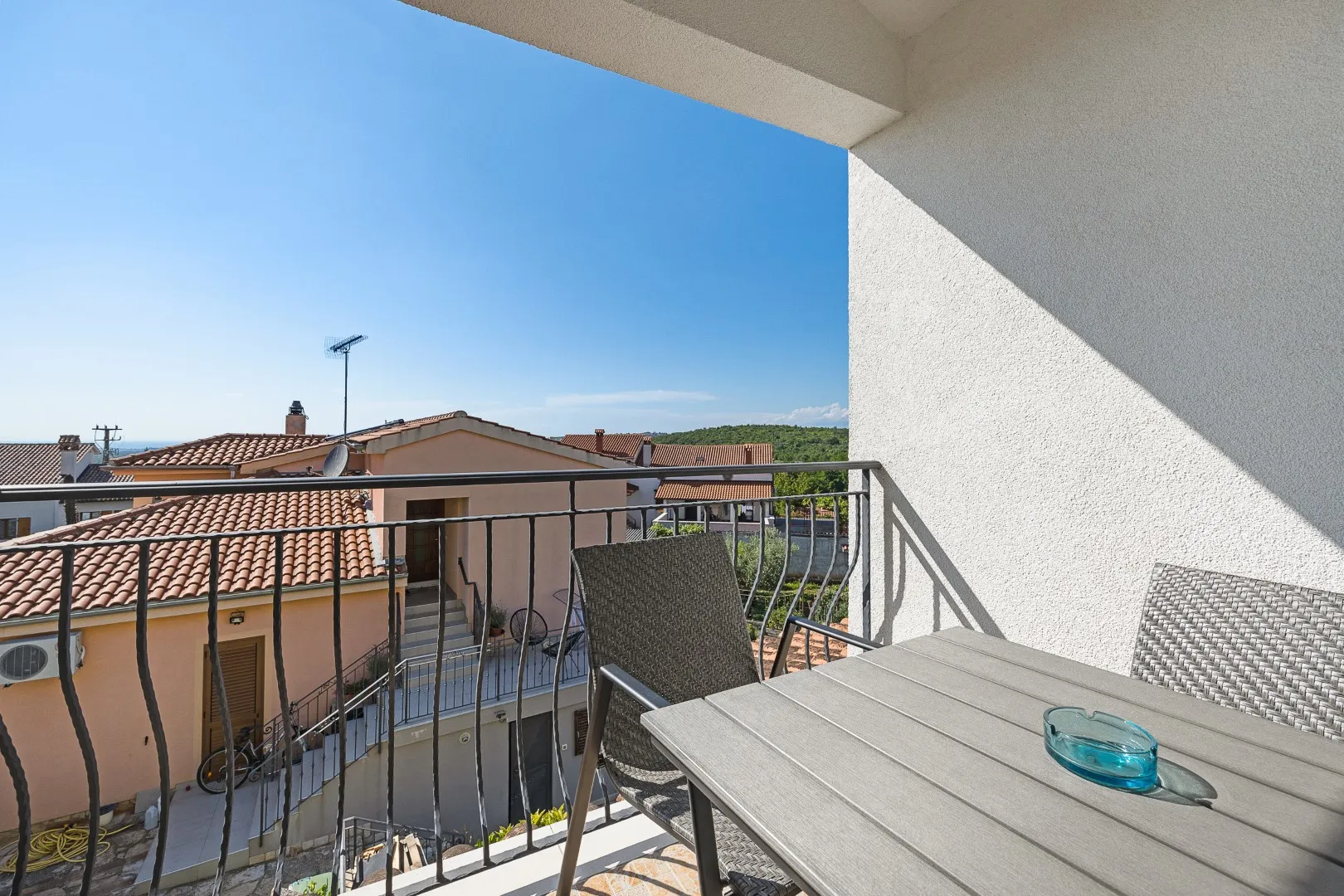 Der Blick vom oberen Balkon über Ziegeldächer hin zu bewaldetem Hinterland