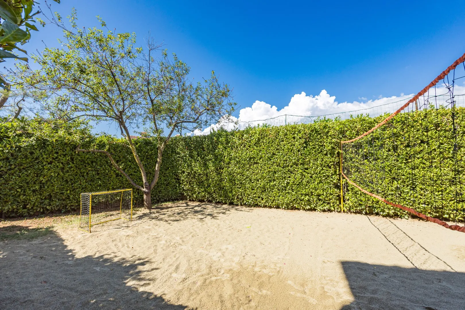 The hedge-lined sand court in the garden, ready for group ball games