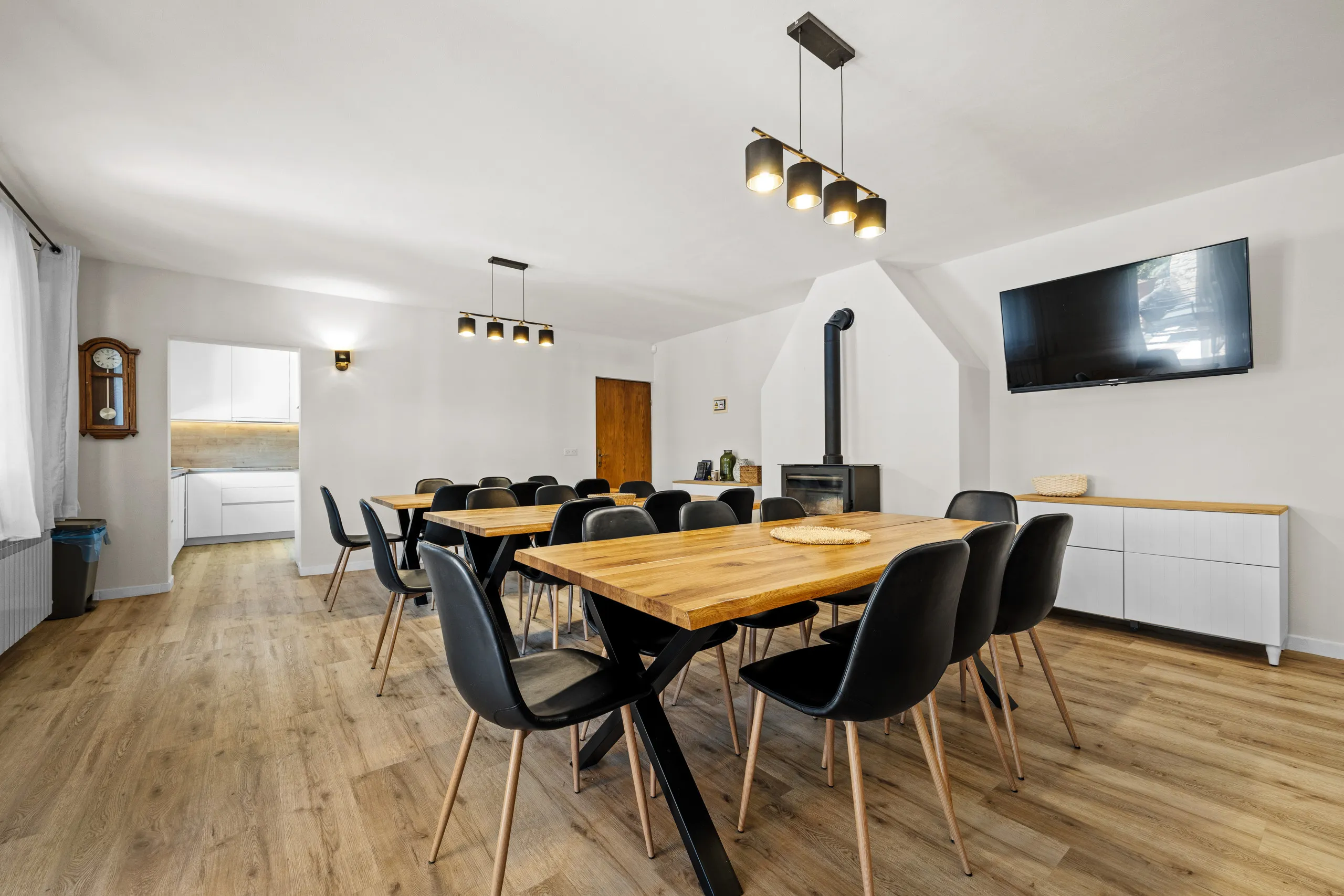 Long dining table with black chairs beside the open-plan kitchen