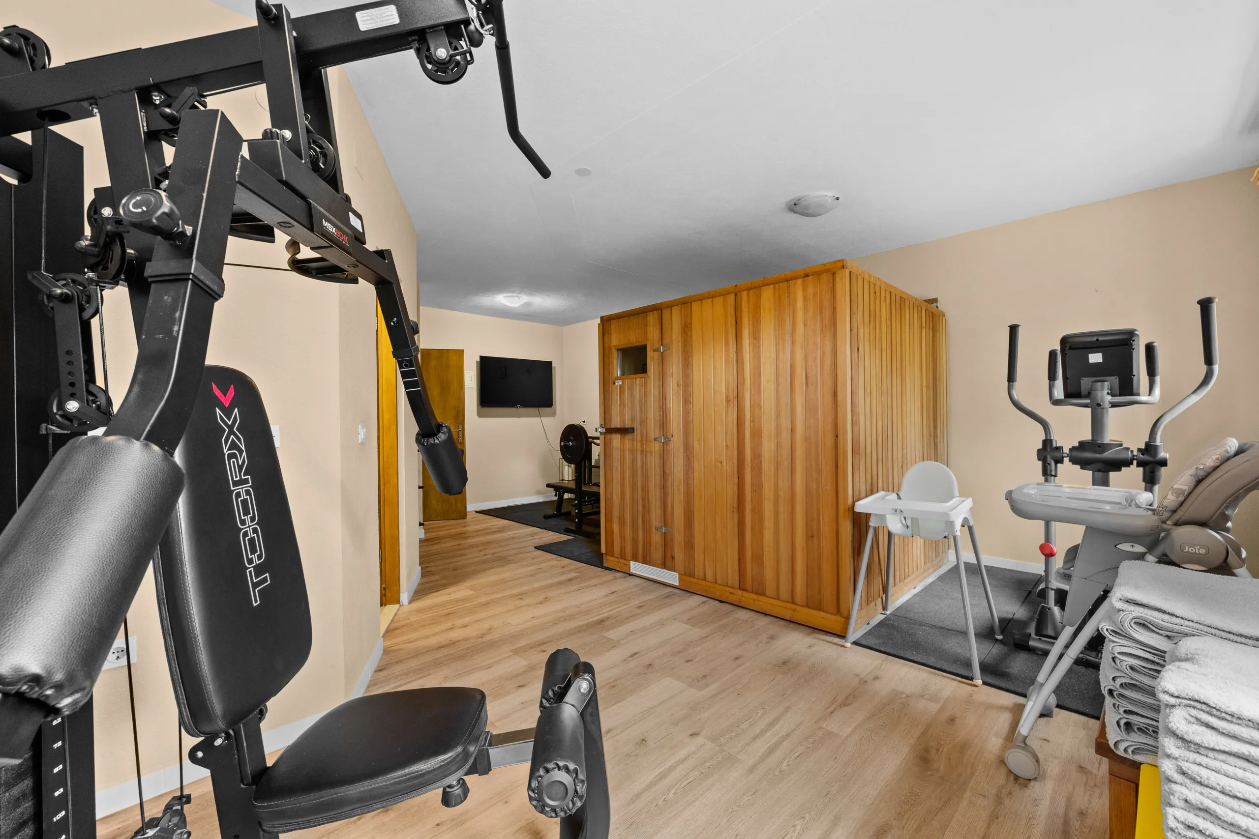 Der Fitnessraum, am hinteren Ende die hölzerne Saunakabine