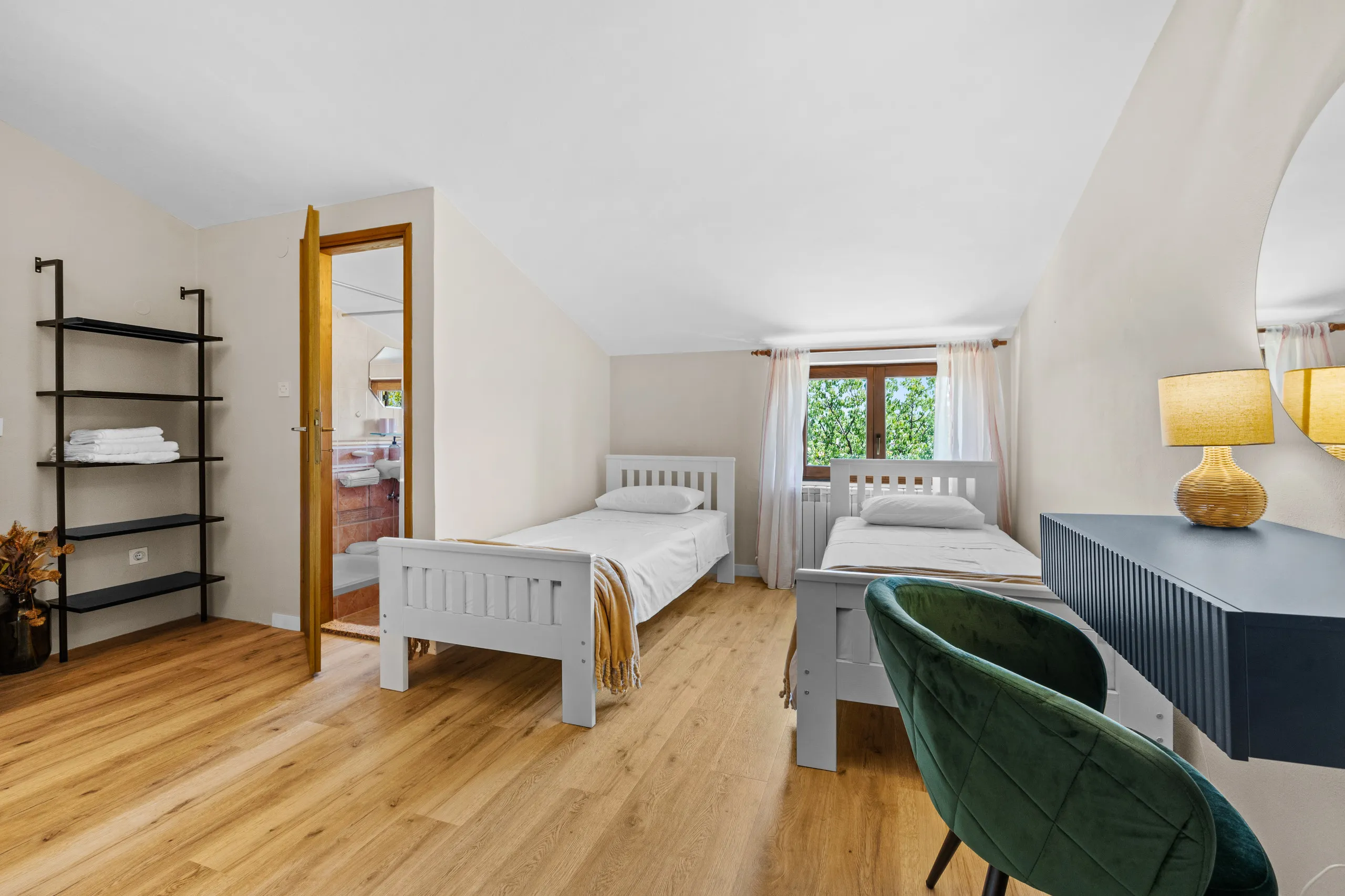 A white double bedroom with wood flooring in morning light
