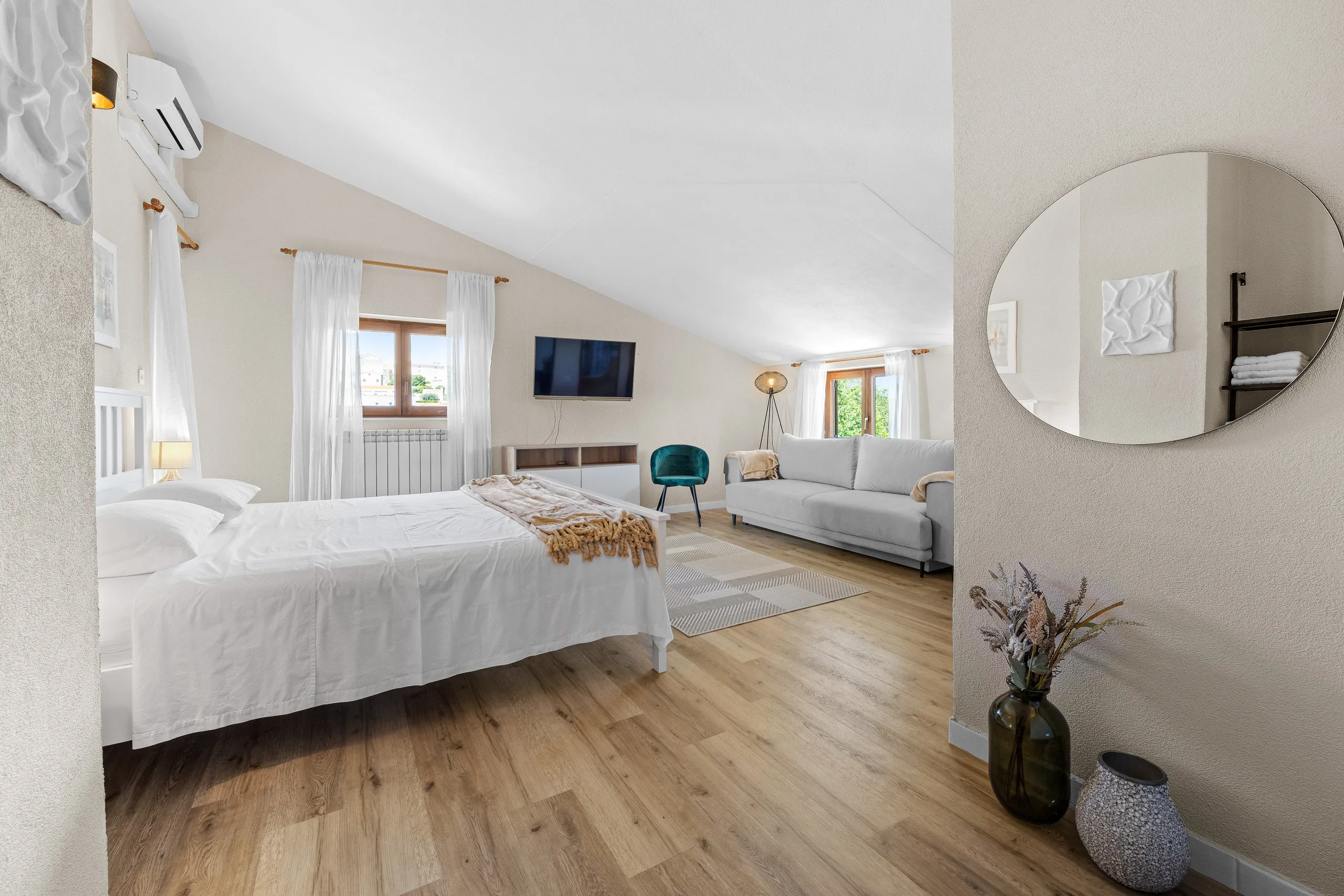 Ein großes Dachzimmer, an der einen Seite ein Doppelbett, an der anderen Sofa und Fernseher