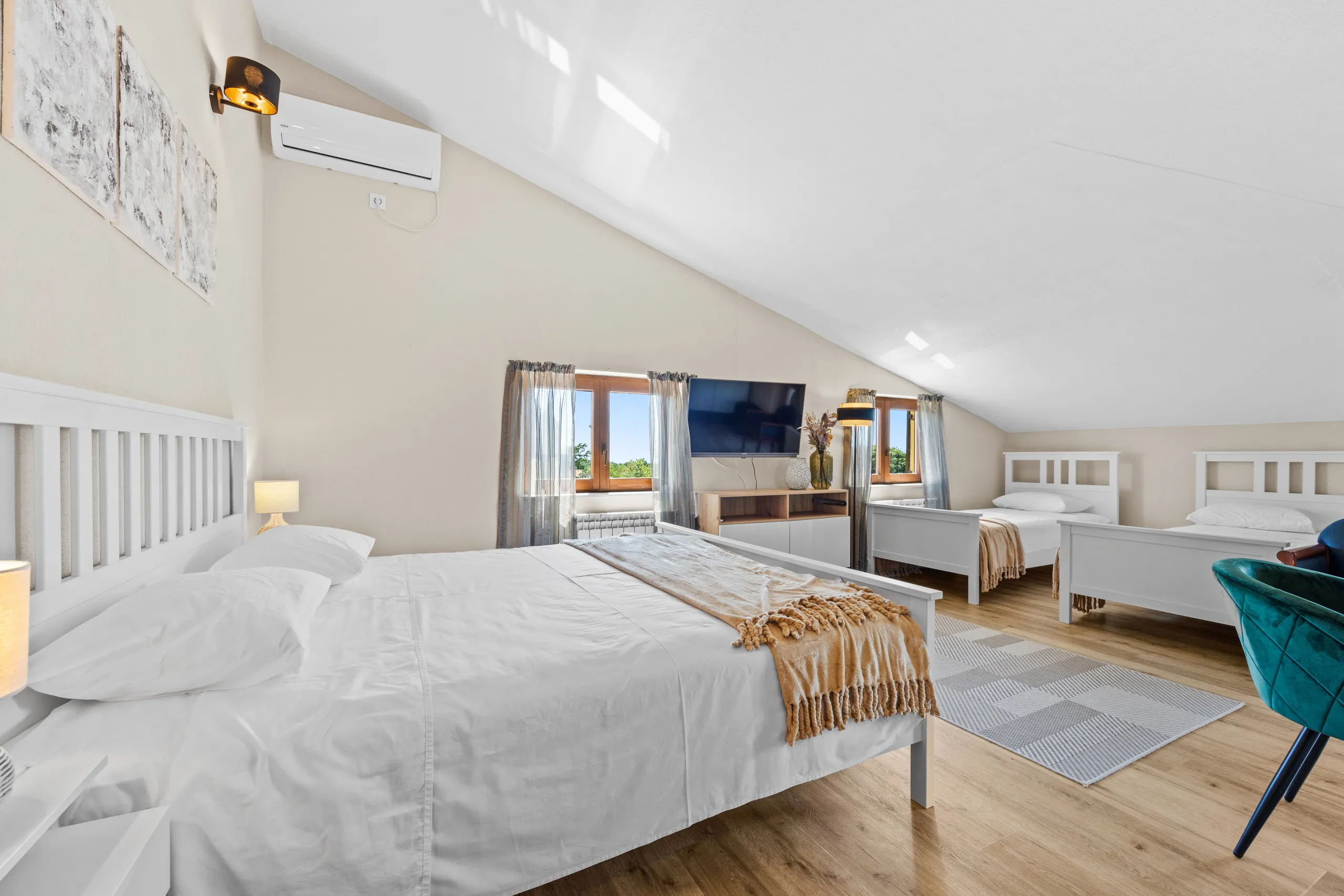 Ein Familienzimmer unter der Dachschräge: ein Doppelbett, gegenüber zwei Einzelbetten