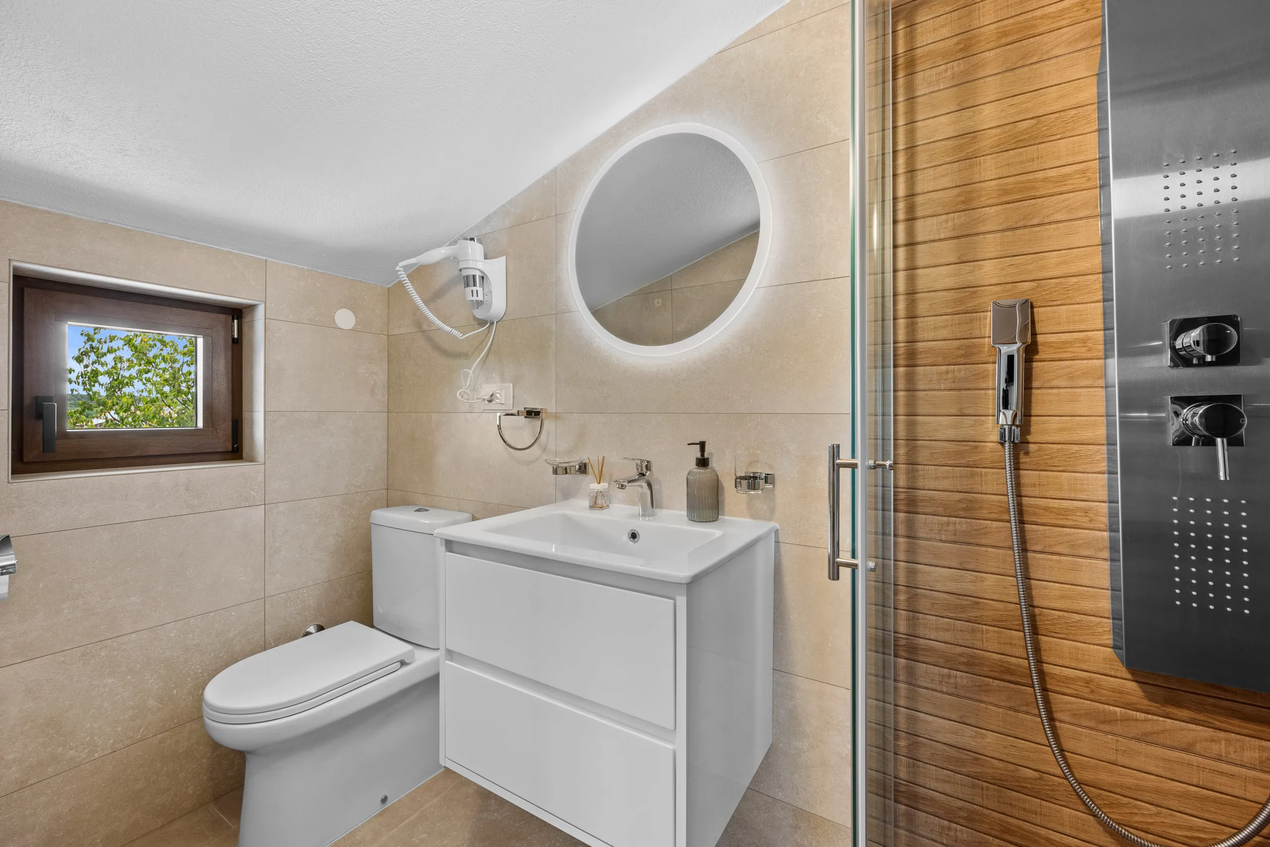 Ein Duschbad mit rundem Spiegel, kleinem Fenster und eichenverkleideter Dusche